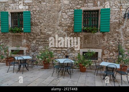 Tavoli da ristorante in una strada stretta nella città vecchia di Sibenik, Croazia Foto Stock