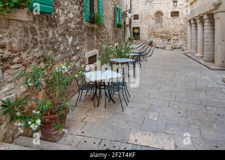 Tavoli da ristorante in una strada stretta nella città vecchia di Sibenik, Croazia Foto Stock