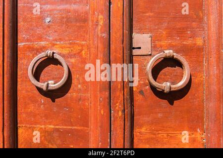 Vecchia porta rossa con maniglie tonde in metallo. Orte, Italia Foto Stock