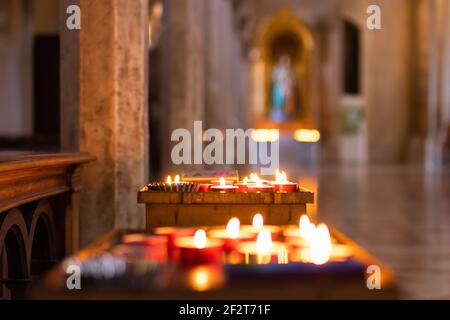 Candele bruciate nella Cattedrale di Santa Maria Assunta a Todi, Umbria, Italia. Messa a fuoco selettiva. Bokeh. Foto Stock