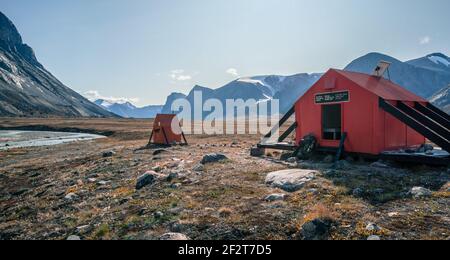 Rifugio di emergenza nella natura artica con uno zaino davanti ad esso . Giornata di sole nella valle del Passo Akshayuk, Parco Nazionale Auyuittuq, Isola Baffin Foto Stock