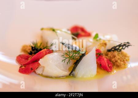 Delizioso antipasto italiano con pesce di mare (Baccala) e pomodori ciliegini. Foto Stock