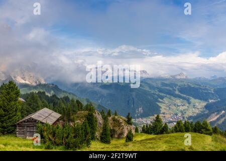 Vista panoramica dalla cima delle montagne alla valle coperta di nebbia nei pressi del paese Colfosco (Calfosch) Dolomiti Italiane, Italia. Foto Stock