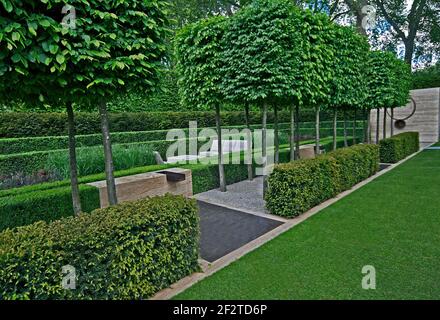 Un classico giardino con un viale di yew, box e carpino portando ad una funzione di acqua e la scultura Foto Stock