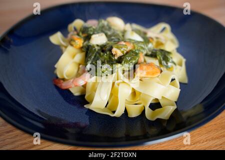 Fettuccine con salsa di crema di formaggio spinaci e pesce arrangiato una piastra Foto Stock