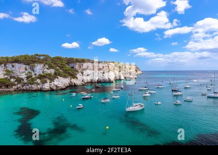 Vista della baia più bella Cala Macarella dell'isola di Menorca con acqua smeraldo e un sacco di yacht sul mare. Isole Baleari, Spagna Foto Stock