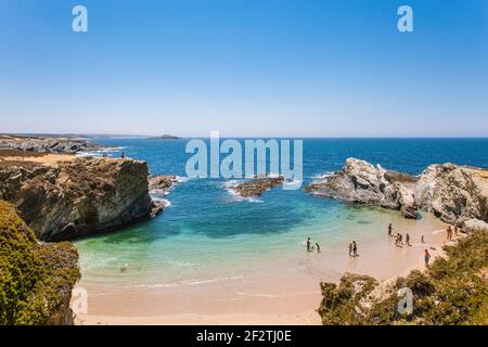 I turisti che si godono il sole e il clima caldo sulla baia della spiaggia di Praia dos Buizinhos, Porto Covo, Alentejo - Portogallo. Foto Stock