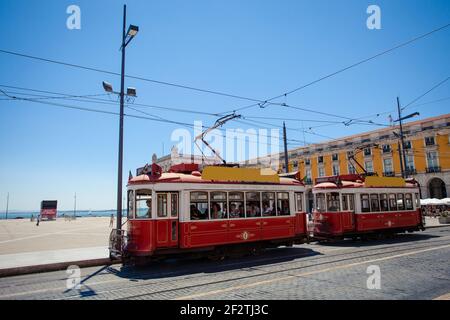 Due iconici tram rossi (elettrico) sullo storico Praça do Comercio, di fronte al porto del Tejo a Lisbona, la capitale del Portogallo. Foto Stock
