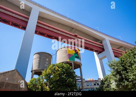 La struttura del ponte del 25 aprile (Ponte de25 Abril) si affaccia sull'iconico serbatoio d'acqua nella destinazione culturale della fabbrica LX, Lisbona, Portogallo Foto Stock