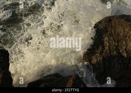 Le onde atlantiche che si propagano nella baia di Carlyon lavando via la sabbia dalla spiaggia e schiantando sopra le rocce seguendo drammaticamente una tempesta al largo del sud Foto Stock