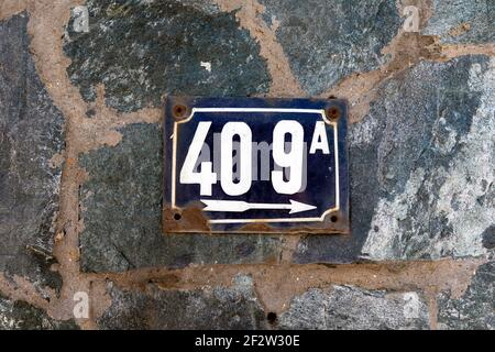 Numero 409 numero di case appartamenti strade. Il numero bianco della lastra di metallo blu alletta quattrocentovinove (409) su un muro di pietra Foto Stock