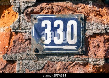 Numero 330 numero di case appartamenti strade. Il numero bianco della casa di metallo blu numero Trecento e trenta (330) su una parete di mattoni Foto Stock