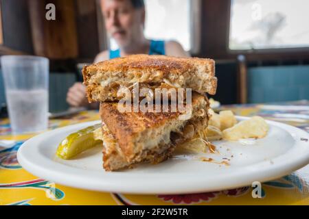 Delizioso panino di formaggio alla griglia in primo piano con l'uomo sullo sfondo Foto Stock