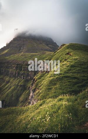 Isole Faroe con vista tempestosa verso mykines sull'isola di Vagar vista dalla cascata di mulafossur. Nuvole basse con le onde dell'oceano atlantico. Foto Stock