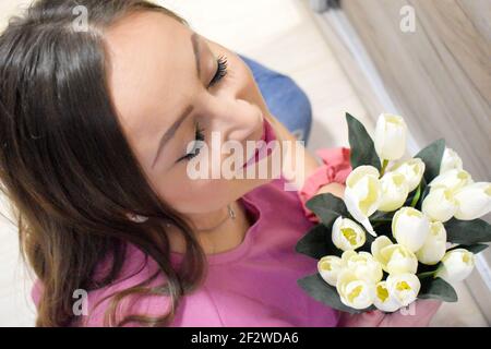 Bella donna che tiene tulipani bianchi all'interno Foto Stock