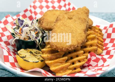 Pesce e patatine calde della friggitrice serviti con waffle fritte e costolette. Foto Stock