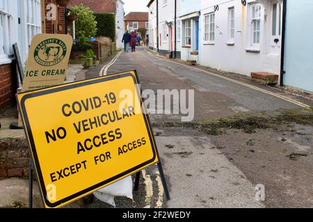 Il cartello stradale di avvertimento Covid-19 indica che l'accesso al veicolo non è consentito. Guida contraddittoria in una piccola e stretta strada a Bosham. Cartello gelato Foto Stock