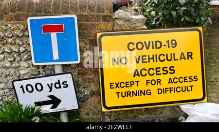 Covid-19 Nessun accesso veicolare tranne per difficoltà di accesso. Segnale stradale di avvertimento giallo per i conducenti che avvisano il potenziale pericolo di una curva difficile. Foto Stock