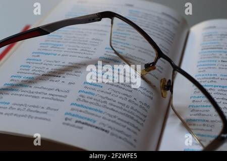 Il lettore è stanco sul suo dizionario, ha tenuto i suoi occhiali sul libro. Foto Stock