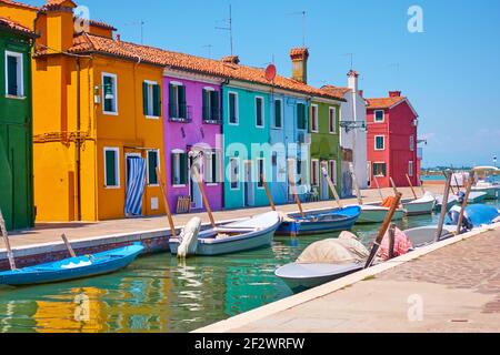 Canale con motoscafi ormeggiati e case colorate a Burano a Venezia. Paesaggio urbano veneziano Foto Stock