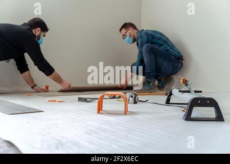 due uomini che installano un pavimento in legno Foto Stock