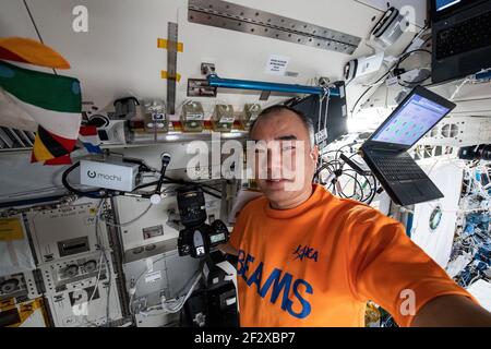 Astronauta e spedizione JAXA 64 l'ingegnere di volo Soichi Noguchi pone con piante che crescono all'interno di contenitori per lo studio delle erbe asiatiche a bordo della Stazione spaziale Internazionale 9 marzo 2021 in orbita terrestre. L'indagine della botanica spaziale sta esplorando i sensi coltivare le piante a rapida crescita usate per la medicina tradizionale e l'aroma di alimento. Foto Stock