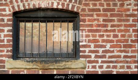 Una finestra con bar, in un muro di mattoni. Questo sembra che potrebbe essere una finestra in una vecchia prigione. C'è spazio per il testo. Foto Stock