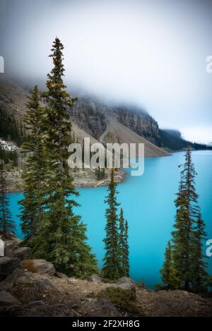 Una mattina in luna presso lo splendido lago Moraine nel Parco Nazionale di Banff. La nebbia offuscava le vette torreggianti, ma il colore del lago era fenomenale. Foto Stock