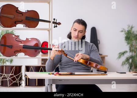 Giovane uomo riparatore che ripara il violino in officina Foto Stock