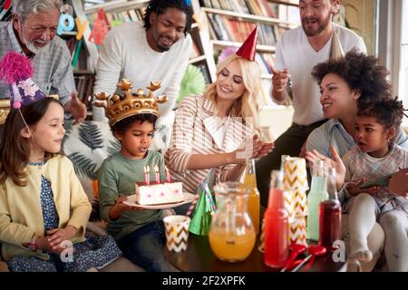 La famiglia e gli amici cantano una canzone di compleanno a un piccolo celebrante durante la sua festa di compleanno in un'atmosfera festosa a casa. Famiglia, celebrazione, insieme Foto Stock