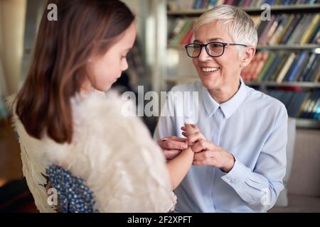 Nonna è piena d'amore per sua nipote mentre si passa il tempo in un'atmosfera rilassata a casa insieme. Famiglia, tempo libero, insieme Foto Stock