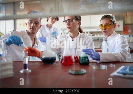 Tecnici di laboratorio che esaminano le reazioni chimiche in laboratorio Foto Stock