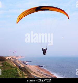 Parapendio in cielo blu sopra le scogliere e le spiagge a Barton on on Sea, Hampshire Foto Stock