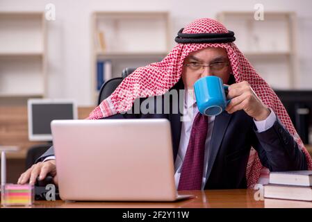 Un dipendente arabo di sesso maschile anziano che beve caffè durante la pausa Foto Stock