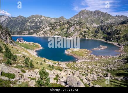 Vista panoramica del lago di Colomers e l'alto rifugio di Colomers, nel parco naturale di aiguastortes nella valle di aran, lerida, spagna Foto Stock