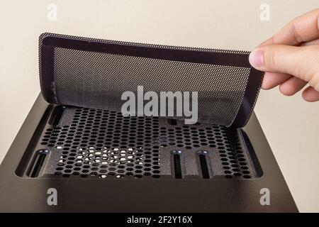 Sollevare manualmente il filtro di raffreddamento della ventola superiore sul telaio nero della torre del computer. Dispositivo magnetico di filtrazione dell'aria per hardware pc moderno. Manutenzione dei PC desktop Foto Stock