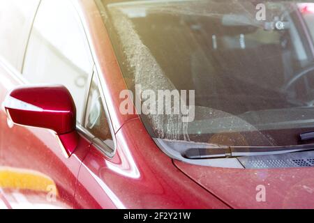 esterno dello specchietto retrovisore coperto da uno strato di polvere di un'auto rossa sporca asciutta con spazzole in gomma sui tergicristalli, nessuno. Foto Stock