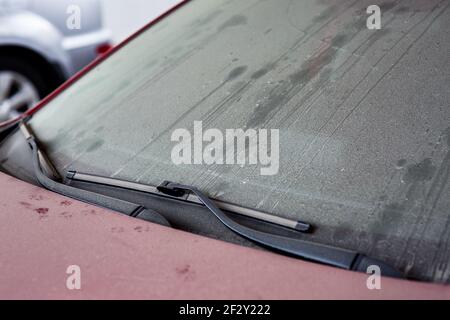 tergicristalli di un'auto rossa sporca ricoperta da uno strato di polvere e fango secco, un primo piano di una parte del veicolo, nessuno. Foto Stock