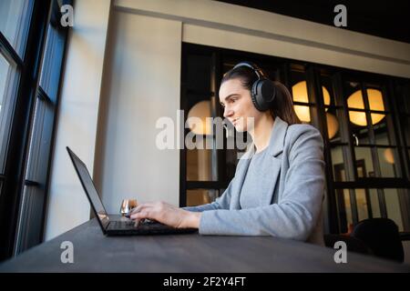la donna d'affari lavora su un computer portatile. Effettua una videochiamata utilizzando gli auricolari Foto Stock