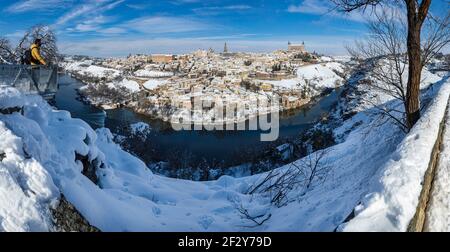 Vista panoramica di Toledo innevata dalla Valle con neve in primo piano una persona in un cappotto giallo guardando da un punto di vista alla spettacolare Foto Stock