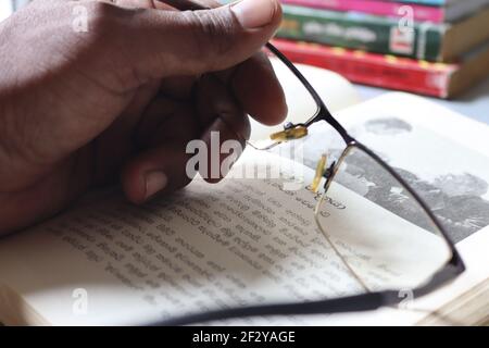 Il lettore è stanco; ha tenuto gli occhiali sul libro. Foto Stock