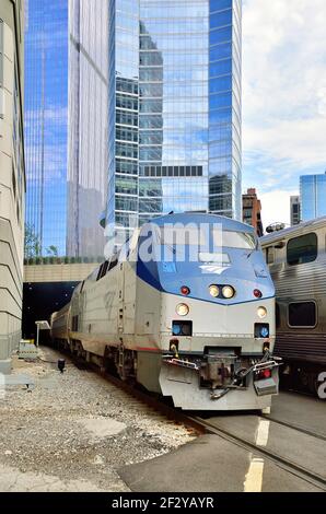 Un treno passeggeri Amtrak in uscita emerge da un tunnel sottostante Grattacieli residenziali e commerciali quando lascia Union Station Centro di Chicago w Foto Stock