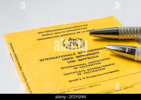 Certificato internazionale di vaccinazione dell'Organizzazione mondiale della sanità. Libro di vaccinazione giallo con in tre lingue con due ballpoint metallici Foto Stock