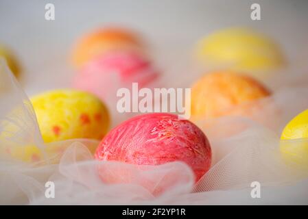 Uova di Pasqua dipinte a mano di colore pastello su tessuto bianco setoso primo piano Foto Stock