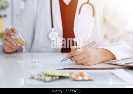 Donna-medico sconosciuto riempie in su la forma di prescrizione in stanza soleggiata, primo piano Foto Stock