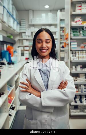 Ritratto di giovane donna afro-americana sorridente farmacista indossando un camice da laboratorio in piedi in farmacia Foto Stock