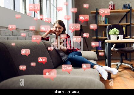 Happy woman chats via smartphone con messaggi di social network, chat e icone degli utenti Foto Stock