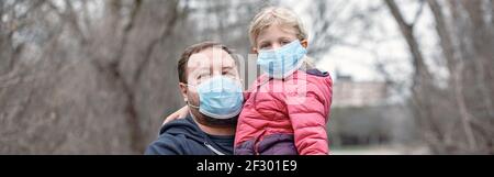 Padre con bambina che indossa maschere sanitarie per il viso all'aperto. Papà e figlia di famiglia si proteggono dalla pericolosa diffusione del virus. Coronavirus Foto Stock