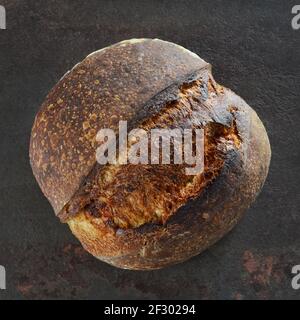 Pane fatto in casa appena sfornato con crosta croccante su uno sfondo scuro primo piano Foto Stock