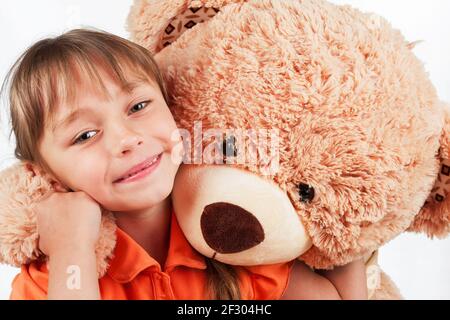 Carina bambina che gioca con il suo amico grande orso pelliccia. Bambina abbracciando il suo orsacchiotto Foto Stock